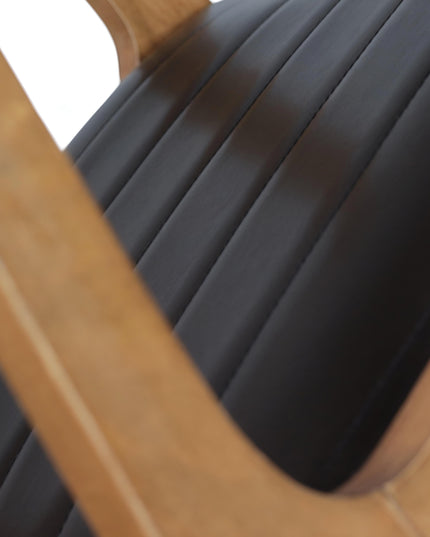 Modern Scandinavian-style dining chair with curved solid wood frame and black upholstered leather seat – ideal for contemporary home interiors, dining rooms, or stylish restaurants