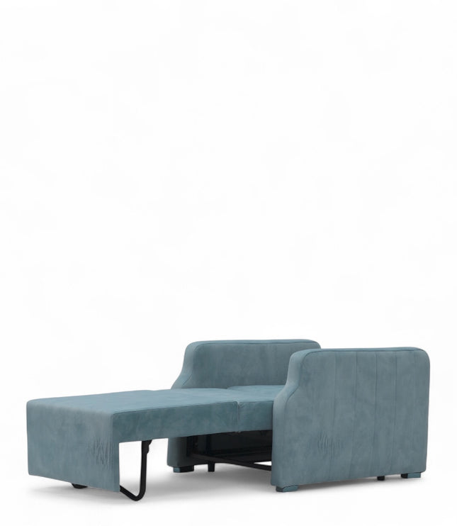 Contemporary blue lounge chair with a pull-out sleeper function and a soft pink accent pillow, featuring plush upholstery and modern lines—ideal for small spaces or guest rooms.