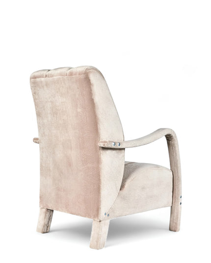 Aura Armchair in beige velvet-style upholstery with scalloped backrest, sculptural arms, and seamless upholstered legs; shown from front-angle, side, and rear perspectives.
