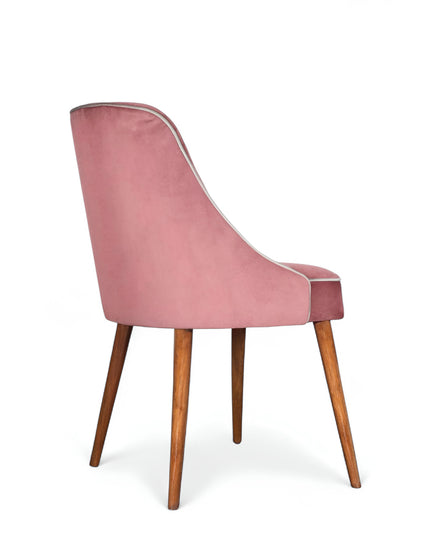 Contemporary side chair with pink curved backrest, studded trim, and wooden legs