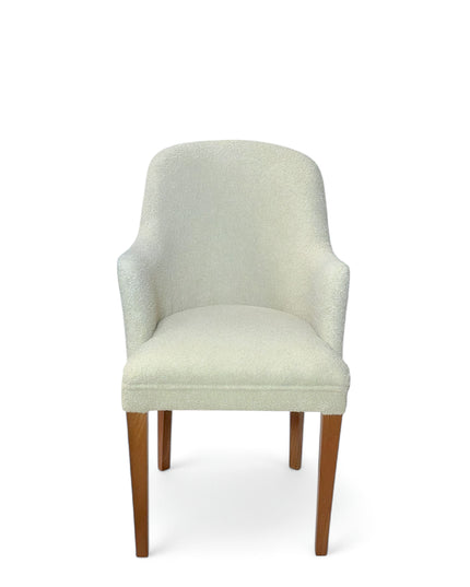 Modern accent chair with ivory bouclé upholstery and wooden legs, featuring a curved backrest and minimalist design