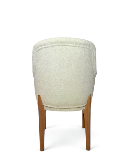 Modern accent chair with ivory bouclé upholstery and wooden legs, featuring a curved backrest and minimalist design