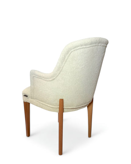 Modern accent chair with ivory bouclé upholstery and wooden legs, featuring a curved backrest and minimalist design