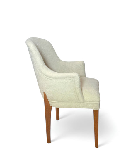Modern accent chair with ivory bouclé upholstery and wooden legs, featuring a curved backrest and minimalist design