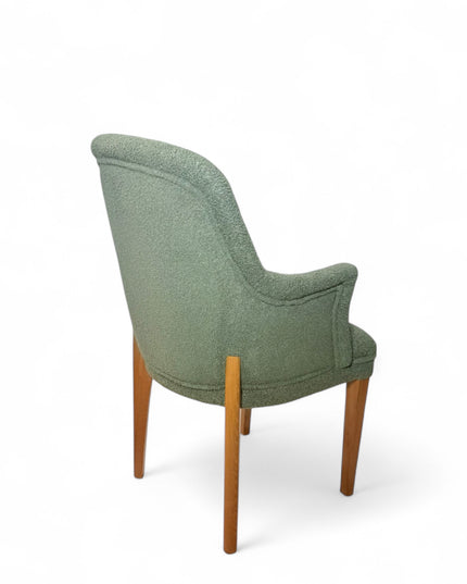 Modern green bouclé accent chair with wooden legs and curved backrest, showcasing a soft textured finish and minimalist arm design