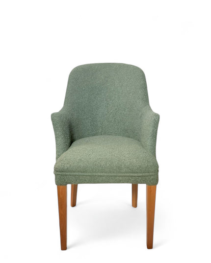 Modern green bouclé accent chair with wooden legs and curved backrest, showcasing a soft textured finish and minimalist arm design