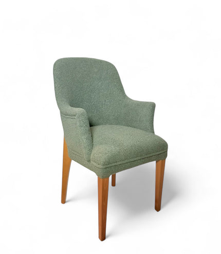 Modern green bouclé accent chair with wooden legs and curved backrest, showcasing a soft textured finish and minimalist arm design