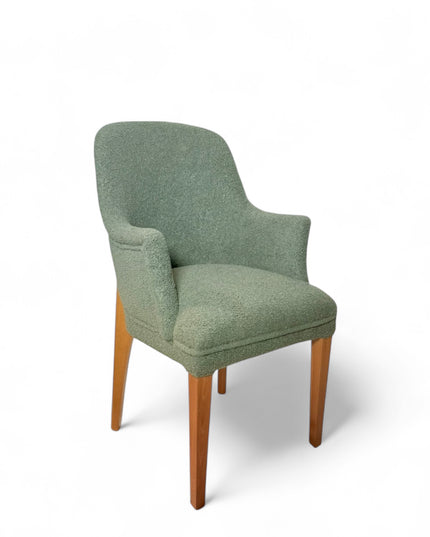 Modern green bouclé accent chair with wooden legs and curved backrest, showcasing a soft textured finish and minimalist arm design