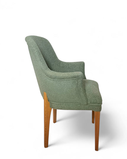 Modern green bouclé accent chair with wooden legs and curved backrest, showcasing a soft textured finish and minimalist arm design