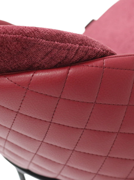 Close-up of a red quilted leather chair with a textured cushion.