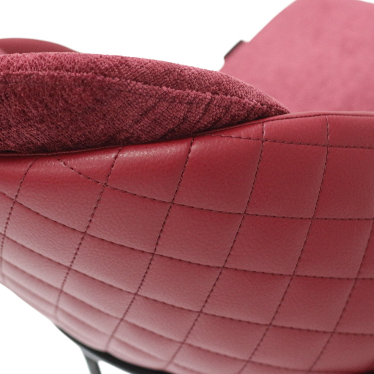Close-up of a red quilted leather chair with a textured cushion.