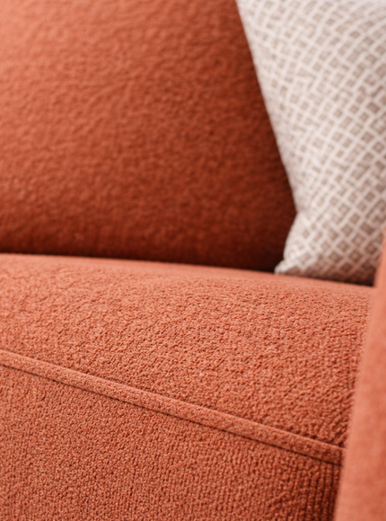 Close-up of a textured orange sofa with a neutral pillow.