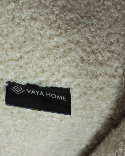 Modern boucle swivel lounge chair with off-white upholstery, curved backrest, and brass base by Vaya Home—ideal for contemporary living room or bedroom seating.
