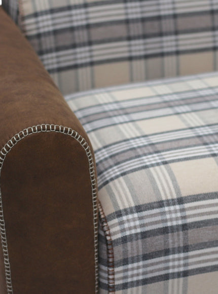 Close-up of a sofa with brown armrest and plaid patterned seat.