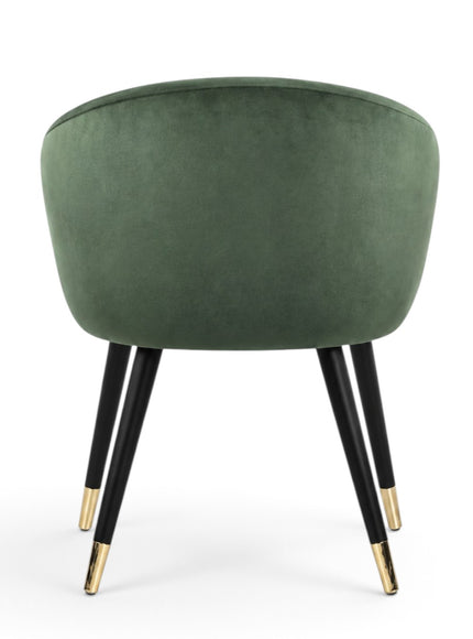 A green velvet barrel-style accent chair with black tapered legs and gold metal tips, shown against a plain white background.