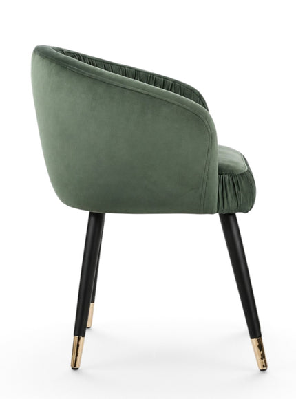 A green velvet barrel-style accent chair with black tapered legs and gold metal tips, shown against a plain white background.