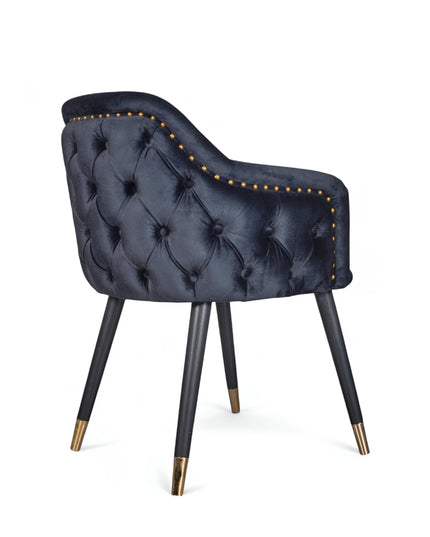 Dark blue velvet accent chair with tufted arm detailing and tapered wooden legs — ideal for modern dining rooms, vanity seating, or boutique interiors.