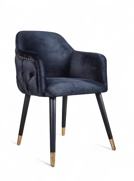 Dark blue velvet accent chair with tufted arm detailing and tapered wooden legs — ideal for modern dining rooms, vanity seating, or boutique interiors.