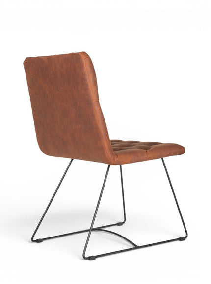Rear angled view of the Vaya Home Hudson dining chair with brown faux leather upholstery and black metal sled base.
