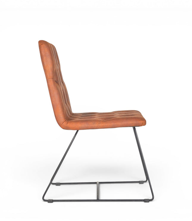 Side view of the Vaya Home Hudson dining chair showing the button-tufted brown faux leather seat, tall backrest, and black metal sled legs.