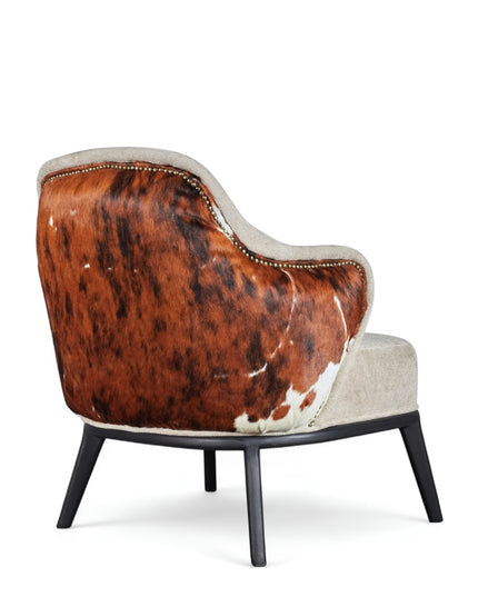 Kalv Armchair with beige fabric front, cowhide-style back panel, brass nailhead trim, and black tapered legs; shown from side, angled front, and rear views.
