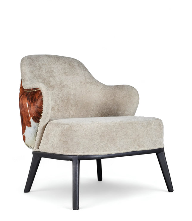 Kalv Armchair with beige fabric front, cowhide-style back panel, brass nailhead trim, and black tapered legs; shown from side, angled front, and rear views.
