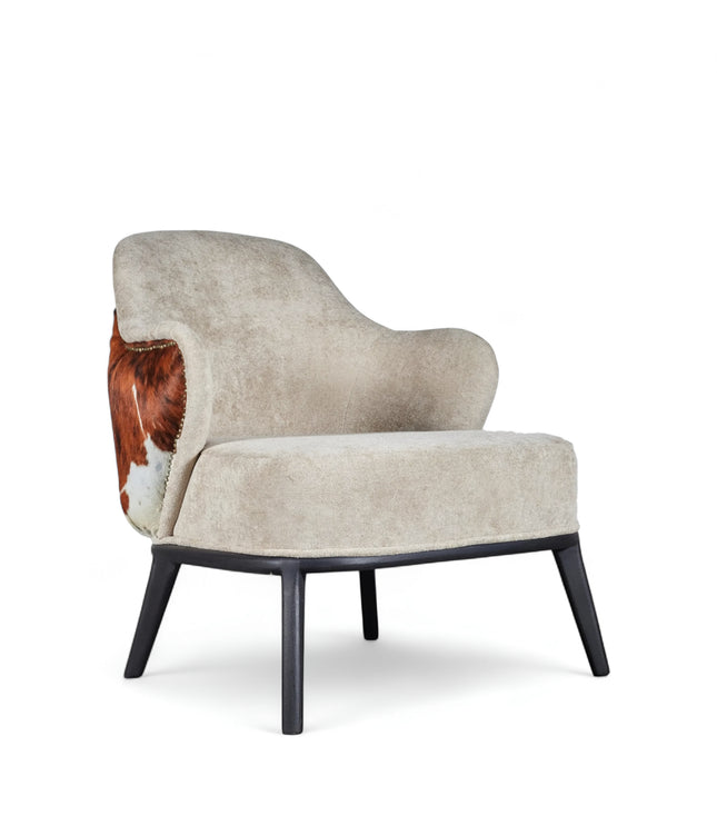 Kalv Armchair with beige fabric front, cowhide-style back panel, brass nailhead trim, and black tapered legs; shown from side, angled front, and rear views.
