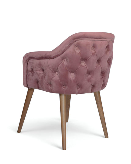 Blush pink velvet accent chair with tufted arm detailing and tapered wooden legs — ideal for modern dining rooms, vanity seating, or boutique interiors.