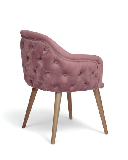 Blush pink velvet accent chair with tufted arm detailing and tapered wooden legs — ideal for modern dining rooms, vanity seating, or boutique interiors.