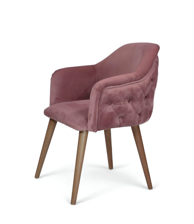 Blush pink velvet accent chair with tufted arm detailing and tapered wooden legs — ideal for modern dining rooms, vanity seating, or boutique interiors.