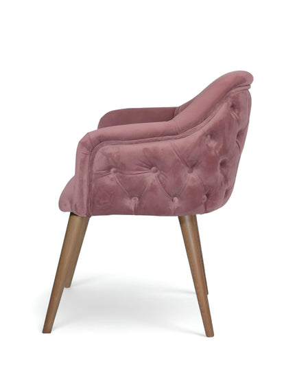 Blush pink velvet accent chair with tufted arm detailing and tapered wooden legs — ideal for modern dining rooms, vanity seating, or boutique interiors.