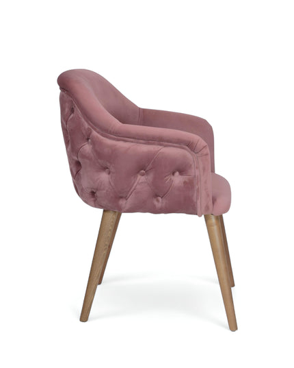 Blush pink velvet accent chair with tufted arm detailing and tapered wooden legs — ideal for modern dining rooms, vanity seating, or boutique interiors.
