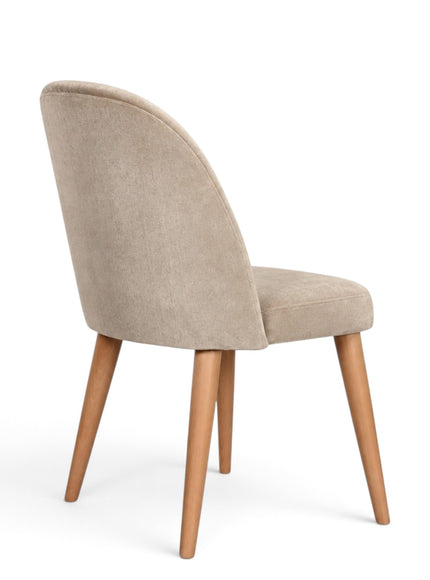 A modern dining chair with a curved backrest upholstered in light beige textured fabric, supported by four tapered natural wood legs, shown from a three-quarter angle on a white background.