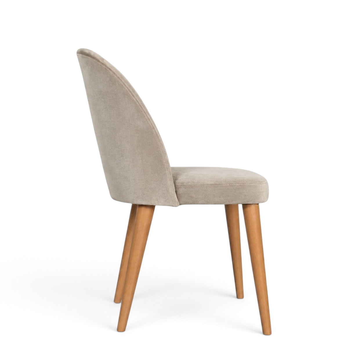 A modern dining chair with a curved back upholstered in light beige velvet, supported by four tapered natural wood legs, shown from a three-quarter angle on a white background.