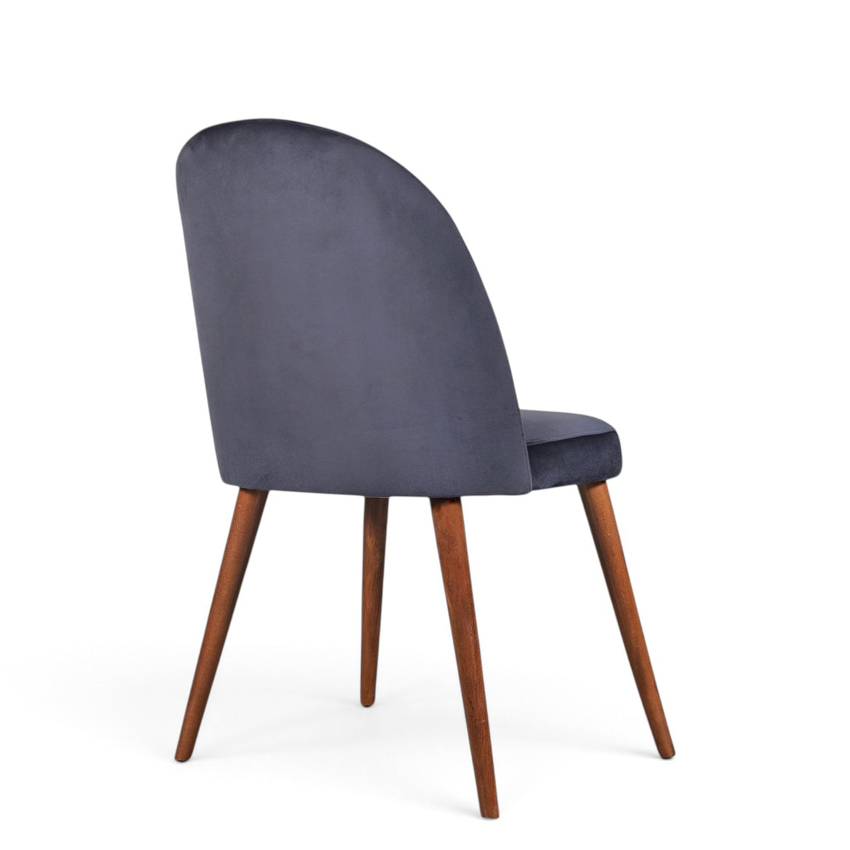 A modern dining chair with a dark slate blue velvet upholstered back and seat, supported by four tapered medium-brown wooden legs, shown from a three-quarter angle on a white background.
