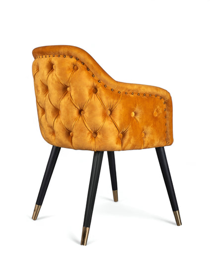 Orange velvet accent chair with tufted arm detailing and tapered wooden legs — ideal for modern dining rooms, vanity seating, or boutique interiors.