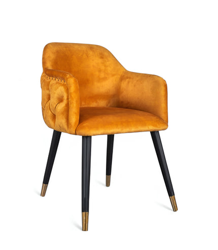 Orange velvet accent chair with tufted arm detailing and tapered wooden legs — ideal for modern dining rooms, vanity seating, or boutique interiors.