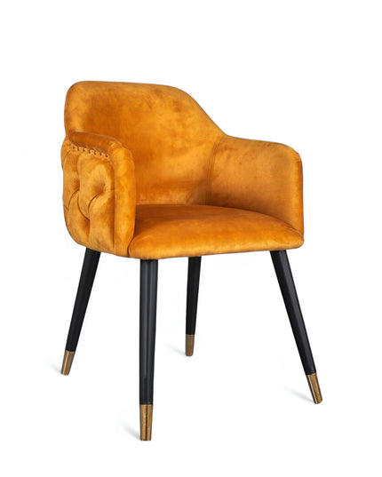 Orange velvet accent chair with tufted arm detailing and tapered wooden legs — ideal for modern dining rooms, vanity seating, or boutique interiors.