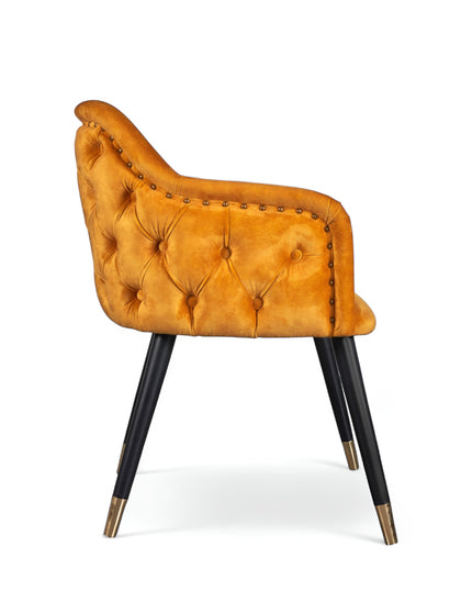 Orange velvet accent chair with tufted arm detailing and tapered wooden legs — ideal for modern dining rooms, vanity seating, or boutique interiors.