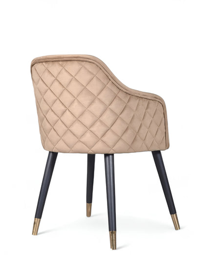 Upholstered beige armchair with diamond stitching, enclosed sides, and tapered black legs with golden tips