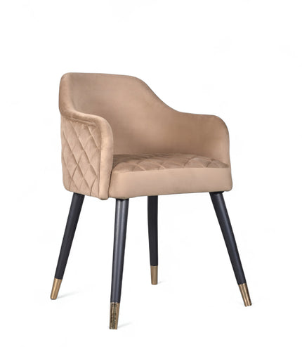 Upholstered beige armchair with diamond stitching, enclosed sides, and tapered black legs with golden tips