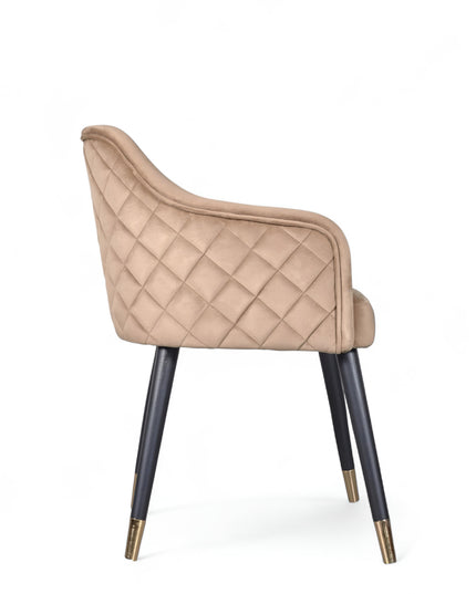 Upholstered beige armchair with diamond stitching, enclosed sides, and tapered black legs with golden tips