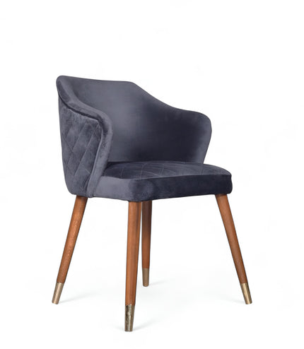 Elegant upholstered dark blue chair with quilted sides, curved backrest, and metal-tipped wooden legs


