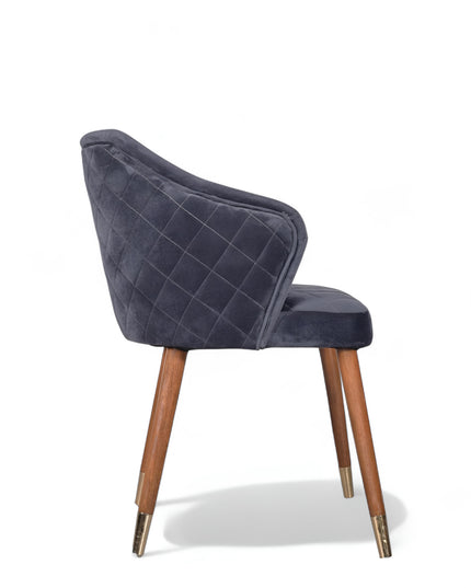 Elegant upholstered dark blue chair with quilted sides, curved backrest, and metal-tipped wooden legs

