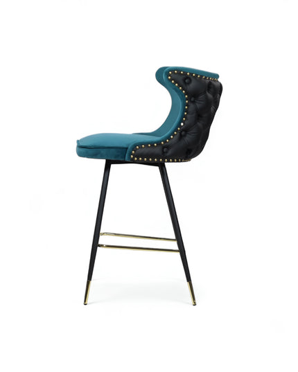 Modern bar stool with a sculpted teal velvet seat and high backrest, featuring black tufted faux leather on the outer back, brass nailhead trim, and slim black metal legs with gold accents and a footrest-ideal for kitchen islands or stylish bar areas