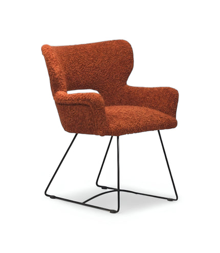 Modern rust orange bouclé accent chair with curved backrest and black metal sled base, perfect for contemporary or eclectic home decor.