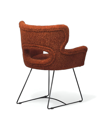 Modern rust orange bouclé accent chair with curved backrest and black metal sled base, perfect for contemporary or eclectic home decor.