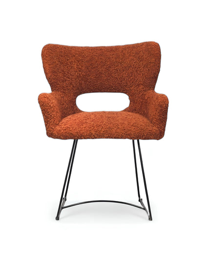 Modern rust orange bouclé accent chair with curved backrest and black metal sled base, perfect for contemporary or eclectic home decor.