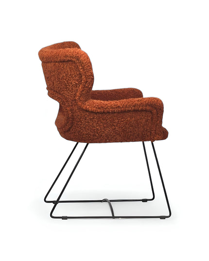 Modern rust orange bouclé accent chair with curved backrest and black metal sled base, perfect for contemporary or eclectic home decor.