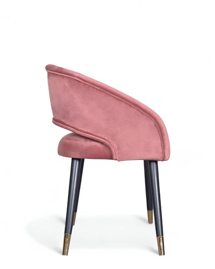 Curved-back pink modern chair with wraparound design, cushioned seat, and brass-tipped black legs